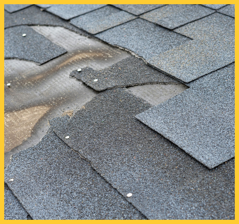 Close-up of damaged roof shingles with missing patches.