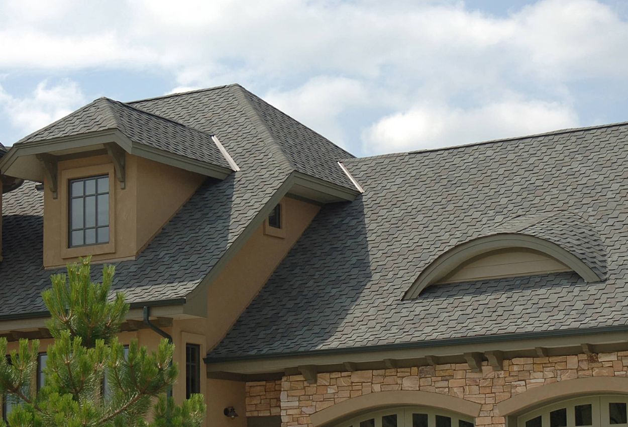 Modern house with detailed shingle roofing and architectural elements.