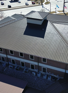 Aerial view of a building with a metal roof design and HVAC units.