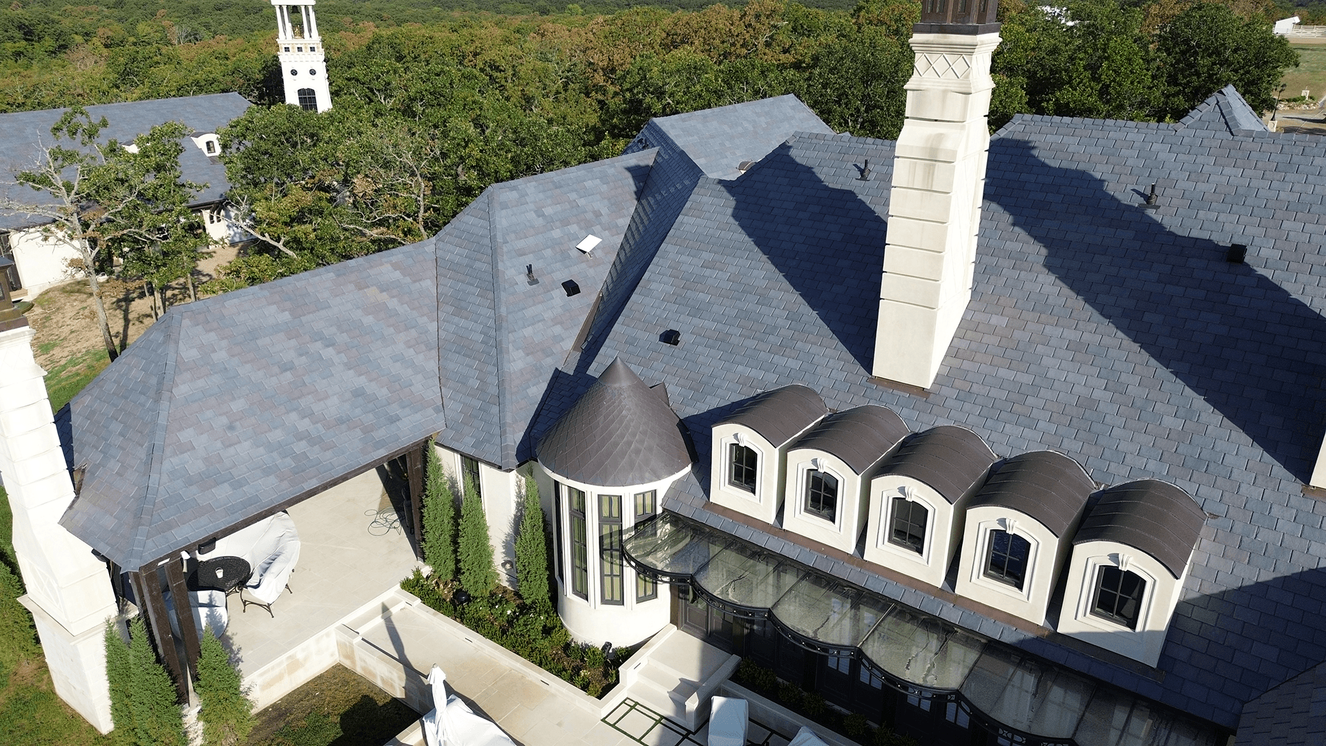 Aerial view of a luxurious mansion with intricate roof design and elegant architecture.